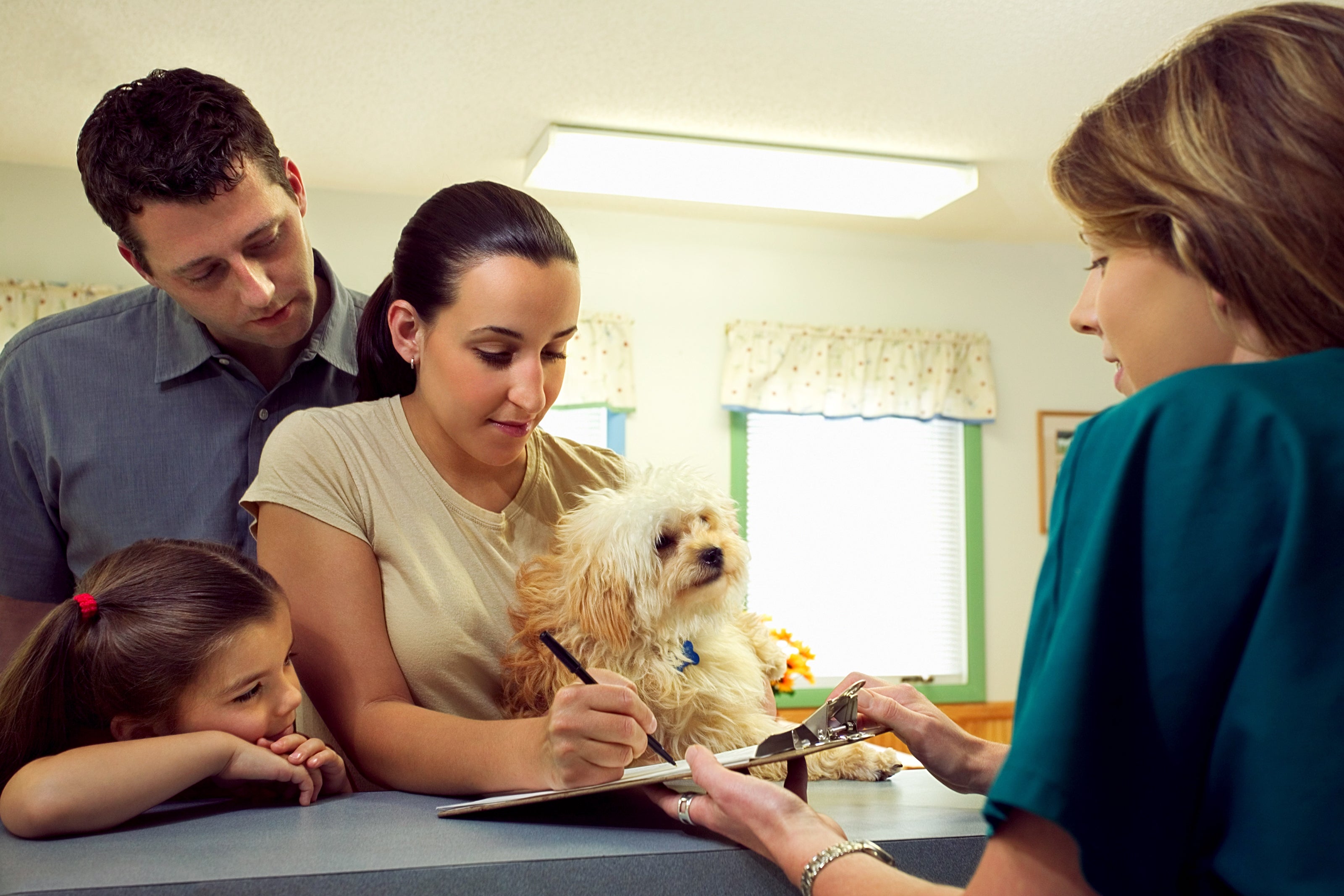 family with dog signing into vets office